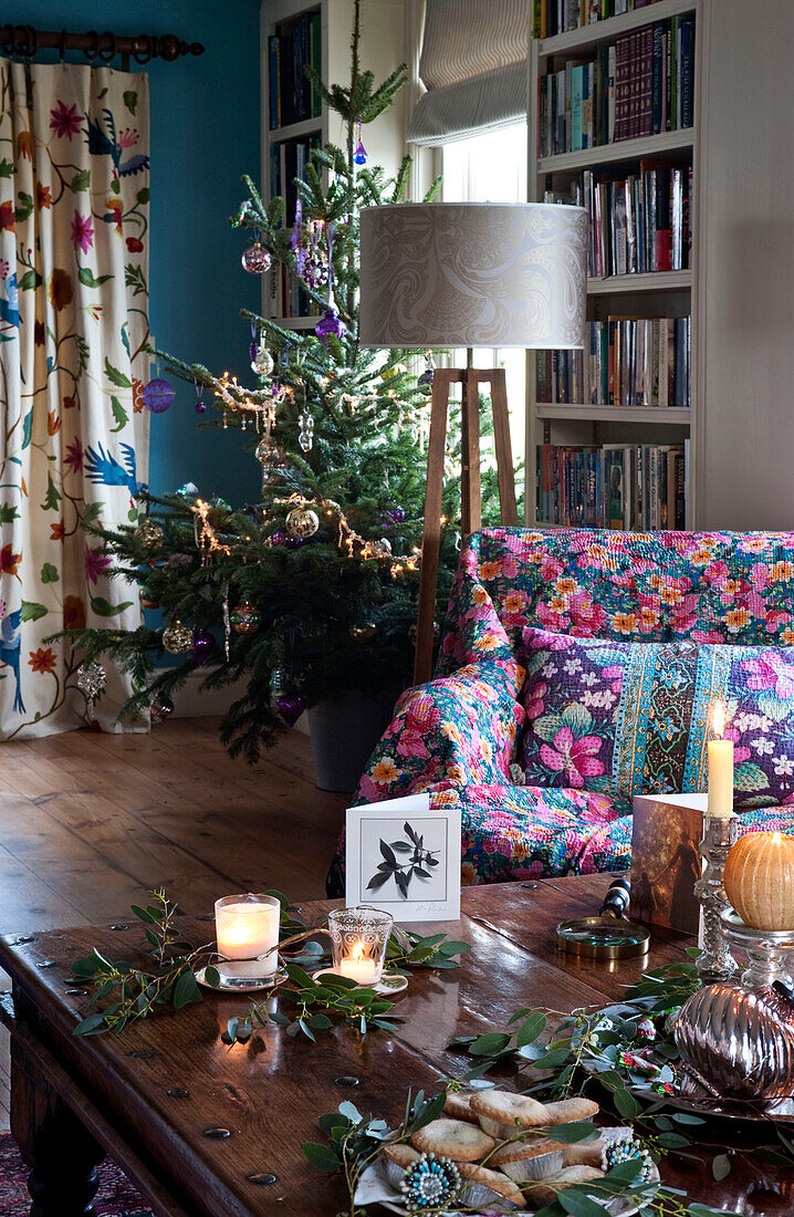 Weihnachtsbaum und Tisch mit brennenden Kerzen und Grünzeug im Landhaus in Hereford