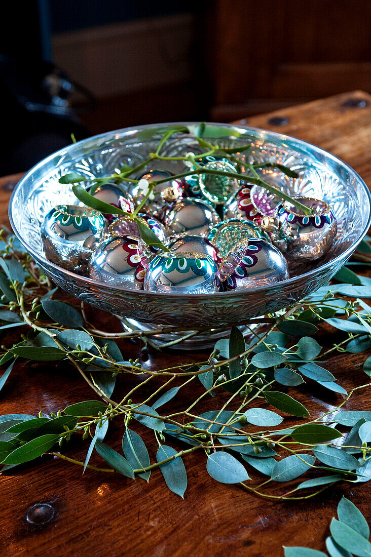 Christmas baubles and green leaves on wooden coffee table