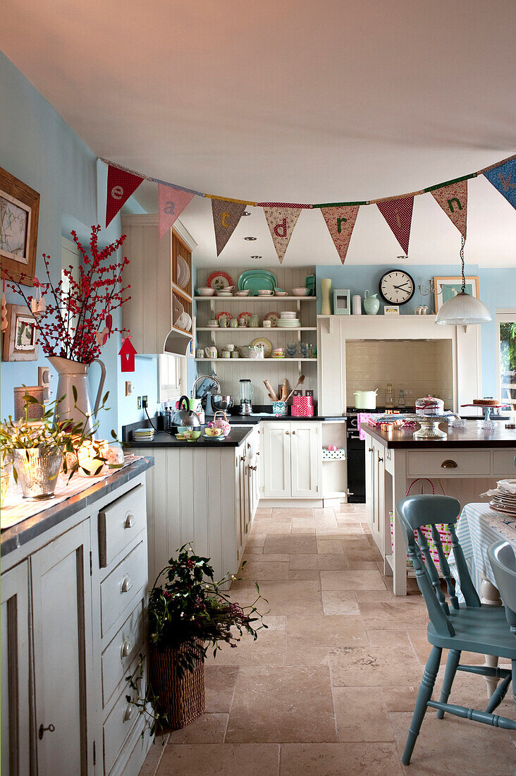 Bunting hangs in pastel blue country style kitchen