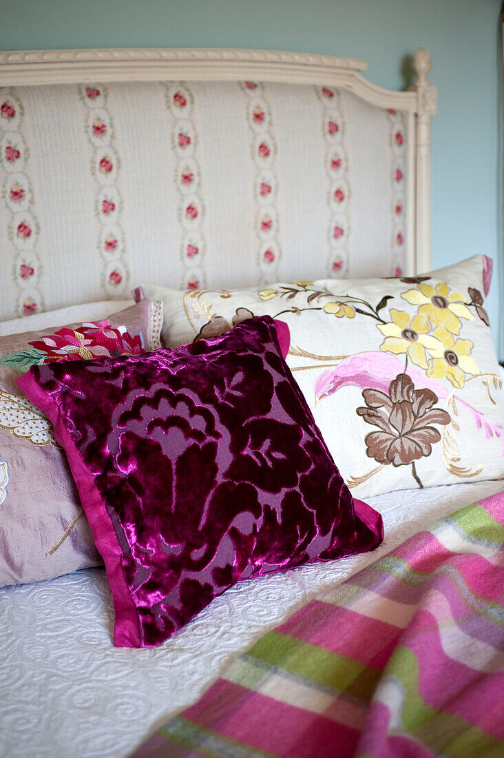 Fuchsia covered cushion on bed with upholstered headboard