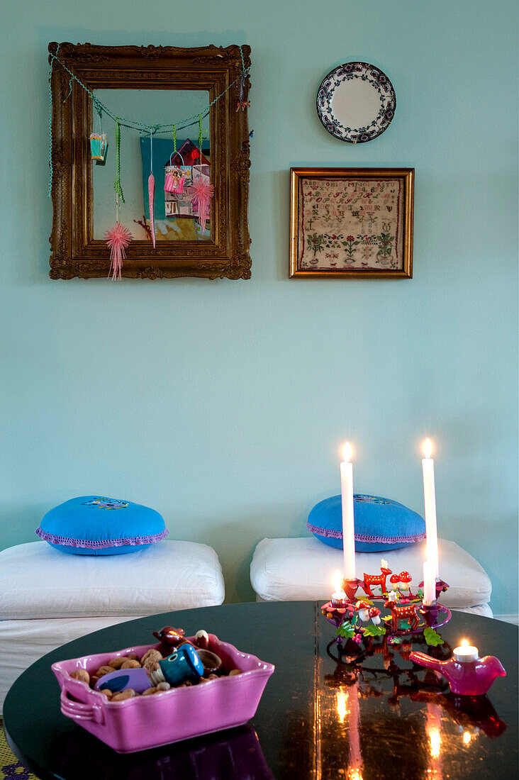 Gerahmte Stickerei und Spiegel hängen an der Wand in einem Haus in Odense mit brennenden Kerzen