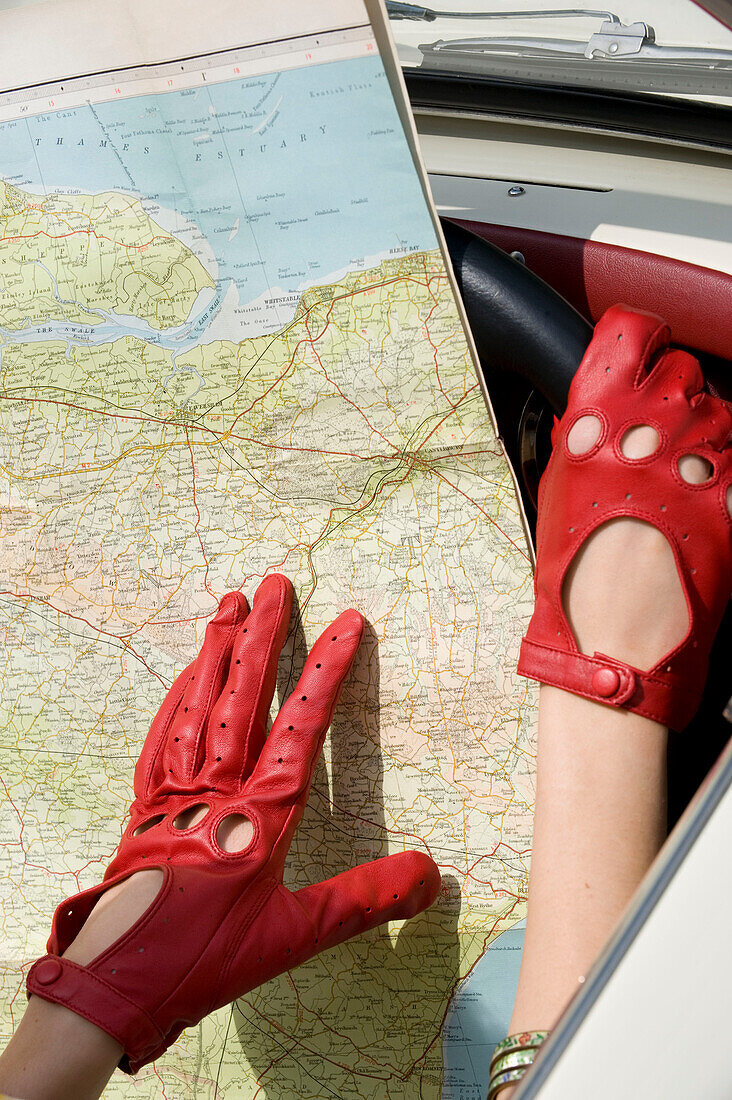 Map with red gloved hands in car interior