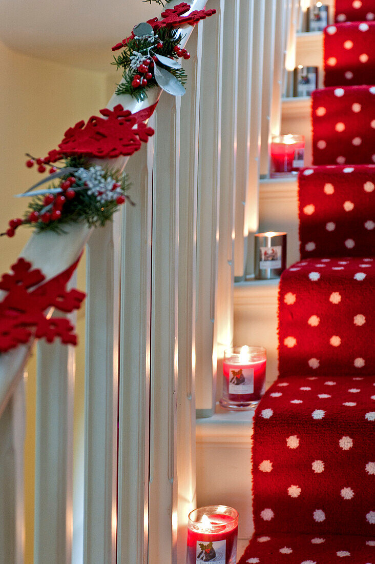 Beleuchtete Kerzen und Weihnachtsdekoration auf der mit Teppich ausgelegten Treppe eines Londoner Hauses, UK