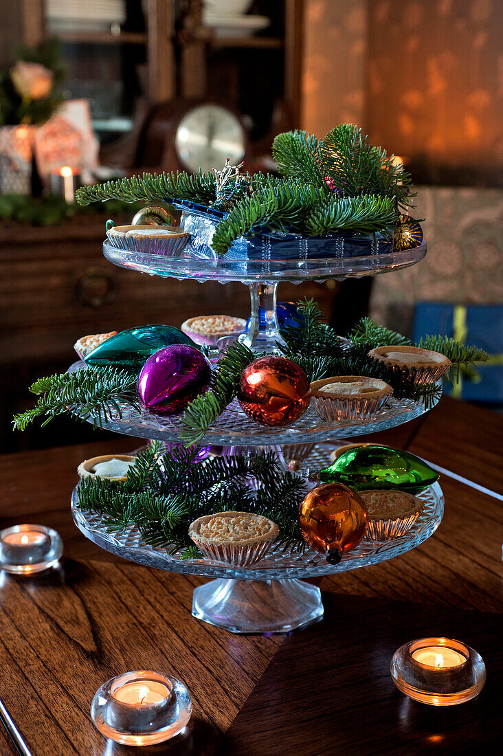 Mince pies and Christmas baubles on glass cake stand in London home UK