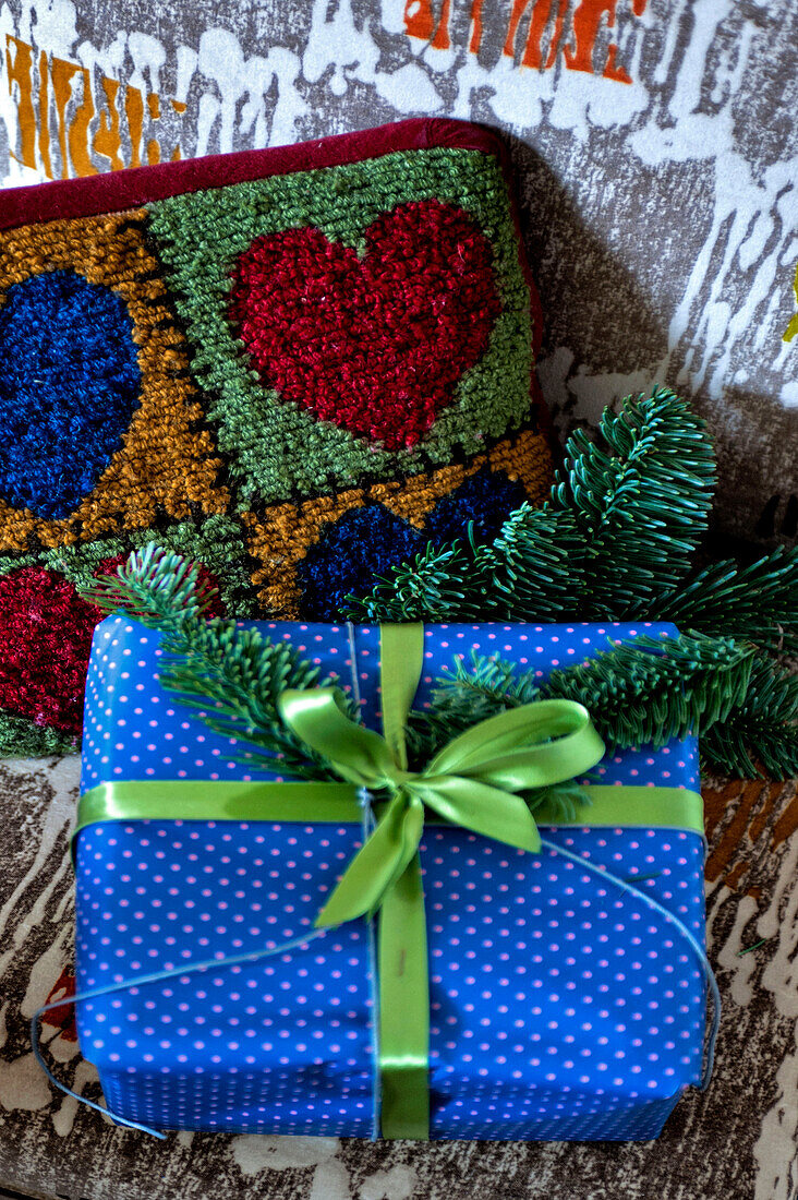 Eingepacktes Geschenk und herzförmiges, besticktes Kissen in einem Londoner Haus, UK