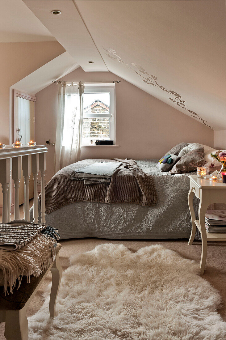 White fur rug in pink attic bedroom of London home UK
