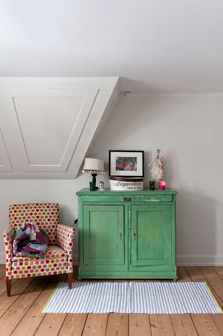 Patterned armchair and green painted cupboard unit in modern Odense bedroom Denmark