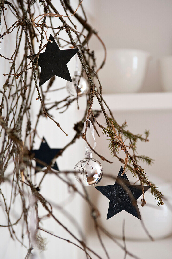 Silver baubles and star shaped decorations on pine branch in London home