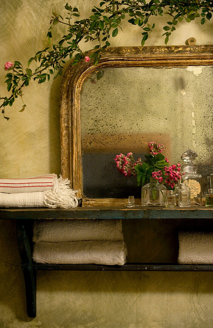 Schnittblumen auf Wandregal mit gerettetem Spiegel und Kletterrose