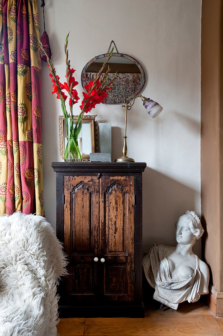 Wooden cabinet and plaster bust with vintage mirror in UK home