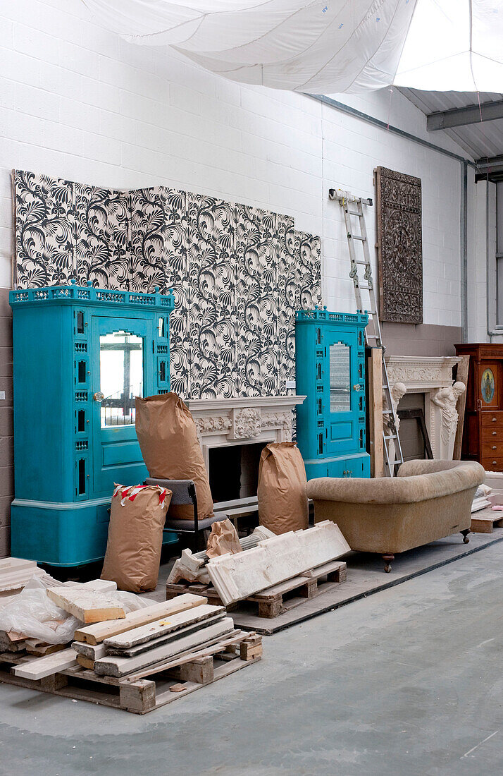 Bemalte Schränke und eine Wand mit Säcken und Paletten in einer Werkstatt UK