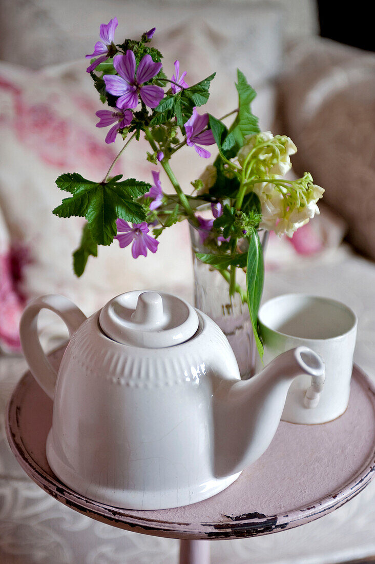 Cut flowers and teapot with cup on side table in London home UK