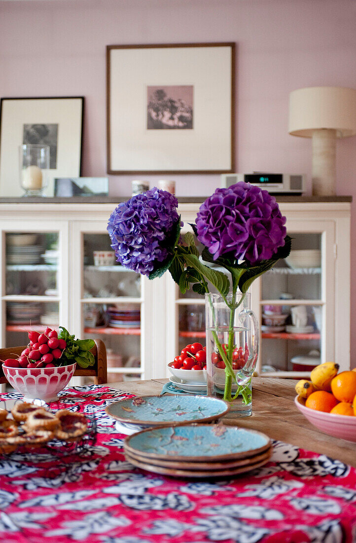 Schnittblumen und Teller auf einem Esstisch in einem Londoner Haus, UK