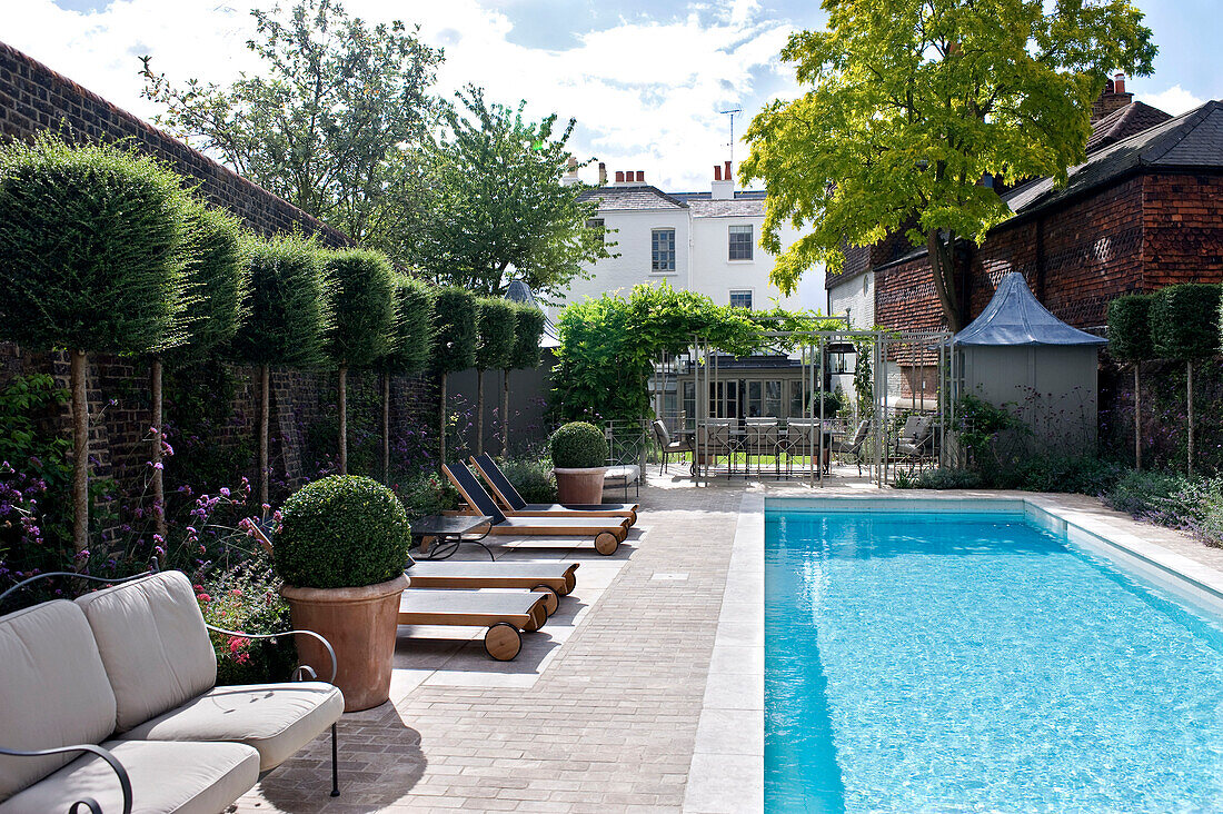 Swimmingpool mit Sitzgelegenheiten im Garten eines Stadthauses in West London England UK
