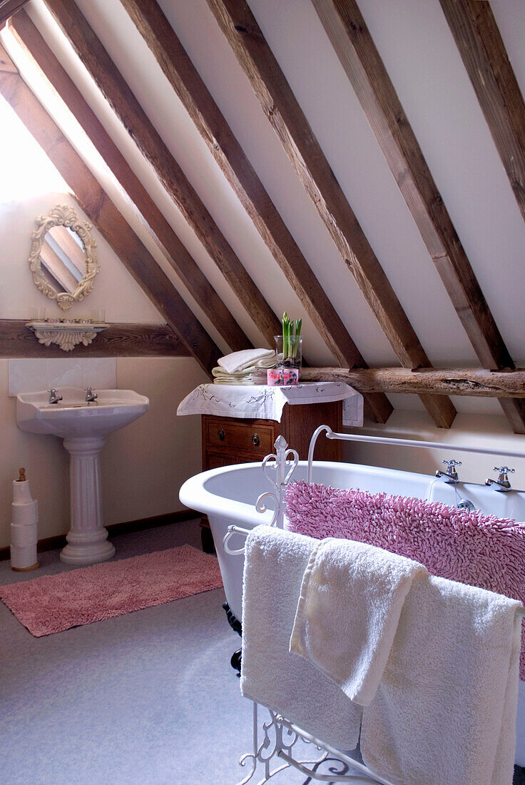 Freestanding bath and towel rail in beamed attic bathroom conversion of rural Suffolk home England UK