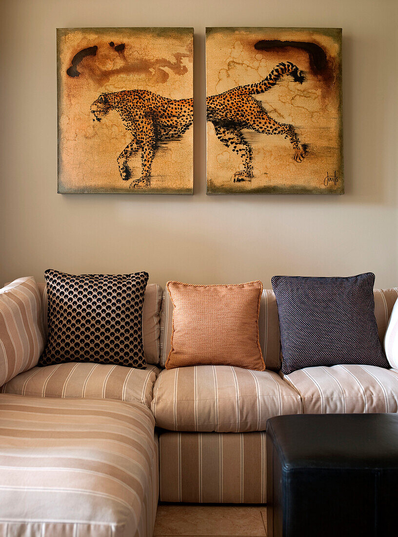 Leopard artwork above striped sofa with cushions in rural Suffolk home England UK