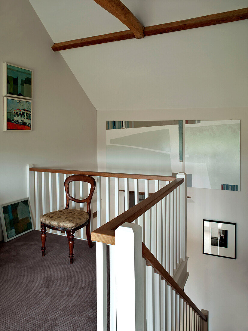 Antiker Stuhl und moderne Kunst im Treppenhaus eines Familienhauses in Suffolk, England, UK