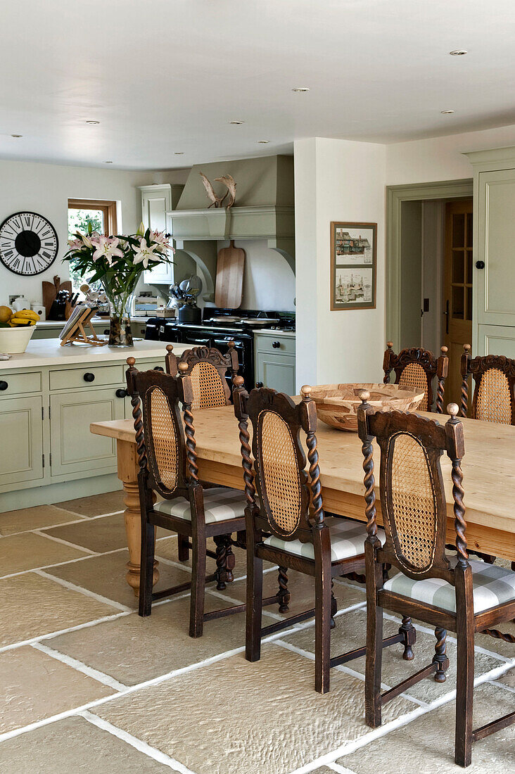 Wooden dining table and chairs in open plan flagstone kitchen of Canterbury home England UK