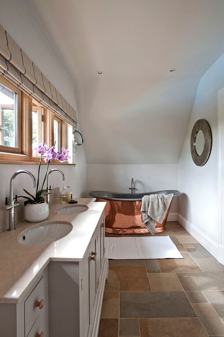 Orchidee auf Doppelwaschbecken mit freistehender Badewanne aus poliertem Messing in Haus in Canterbury England UK