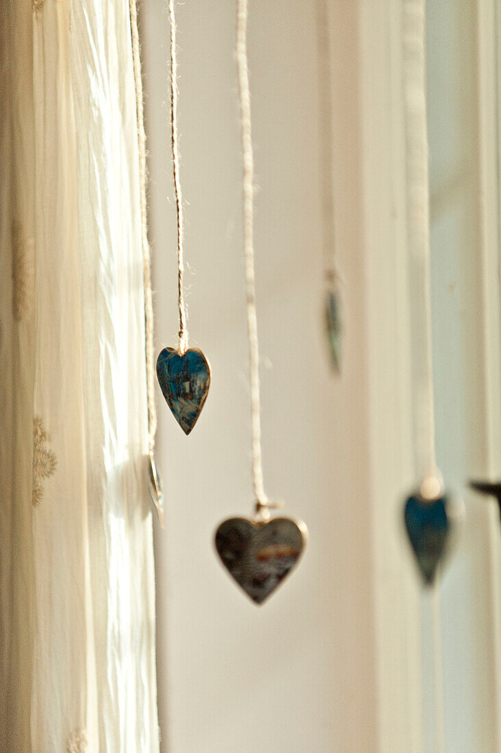 Vier an einer Schnur hängende Herzformen im Haus einer Familie in Forest Row, Sussex, England, UK