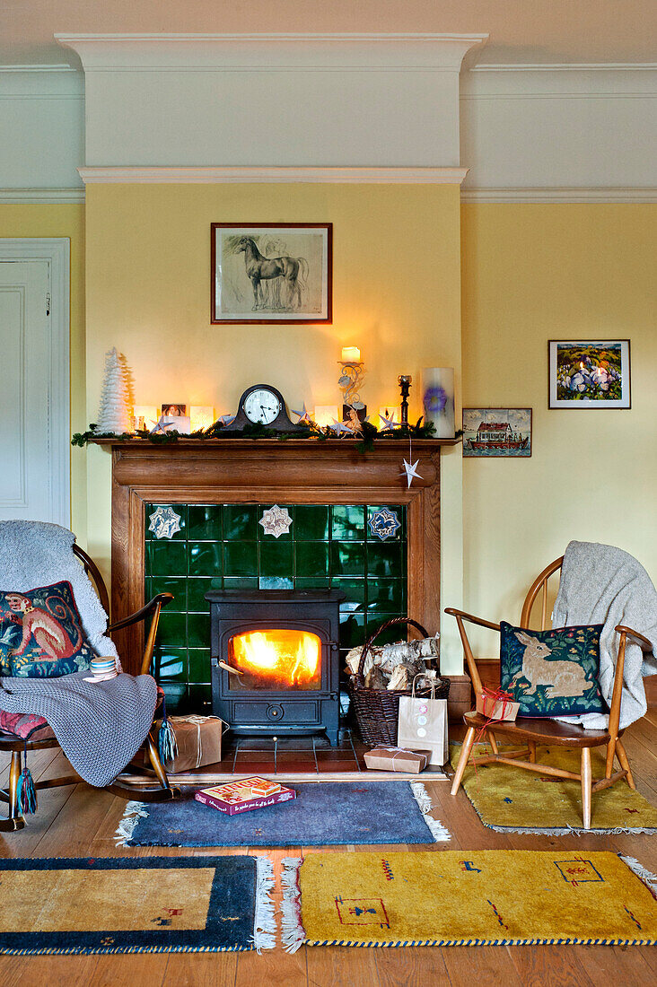 Holzstühle und beleuchteter Holzofen in einem Einfamilienhaus in Forest Row, Sussex, England, UK