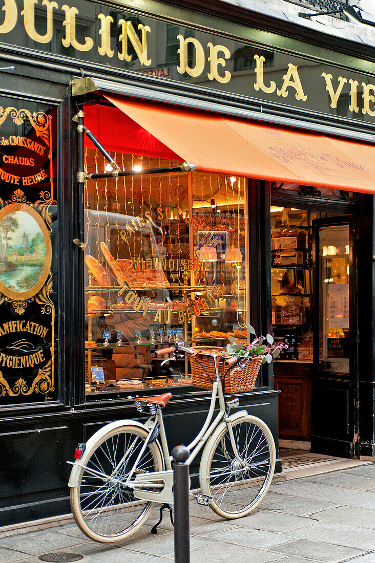 Bicycle parked on pavement outside delicatessen in Paris, France