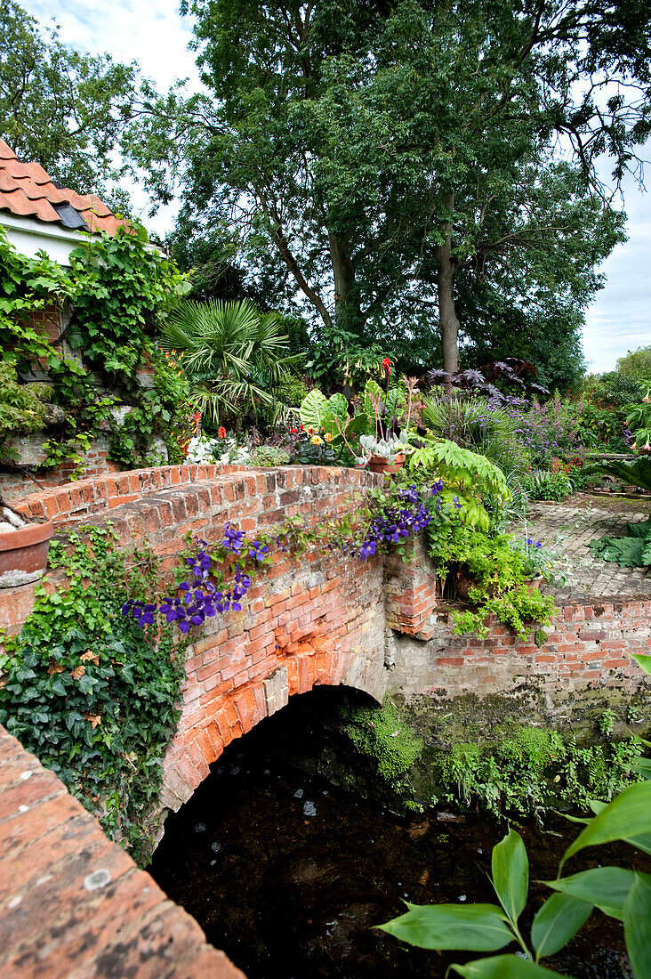 Brick footbridge in rural garden exterior of Suffolk country house England UK