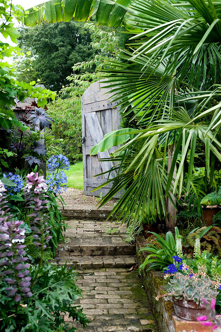Backsteinpfad und offenes Tor im Garten eines Hauses in Suffolk, England, UK