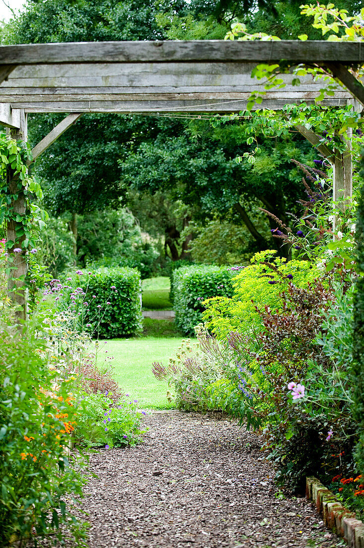 Holzschnitzelpfad und Pergola im Garten eines Landhauses in Suffolk, England, UK