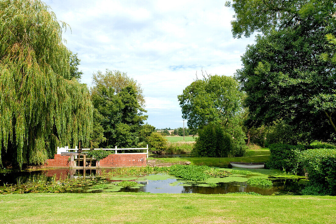 Bäume um einen Teich auf dem Gelände eines Landhauses in Suffolk, England, UK