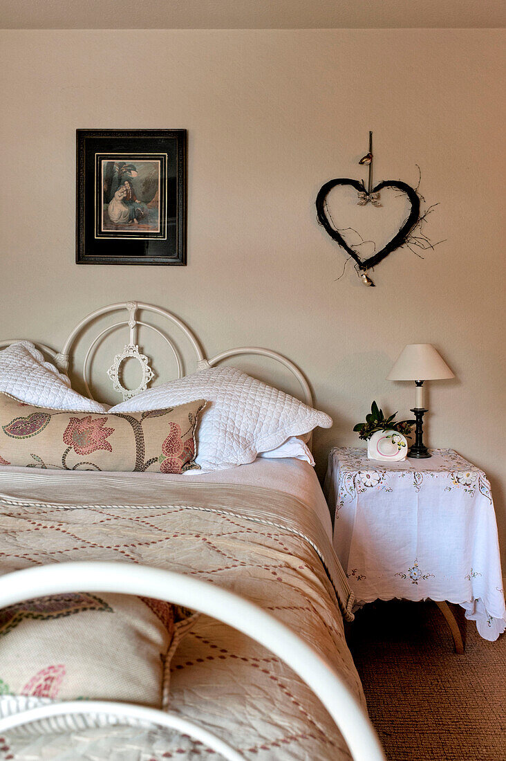 Herz an der Wand über einem Nachttisch aus Spitze in einem Haus in Walberton, West Sussex, England, UK