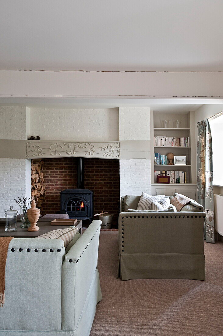 Riveted sofas and woodburning stove in living room of Buckinghamshire home, England, UK