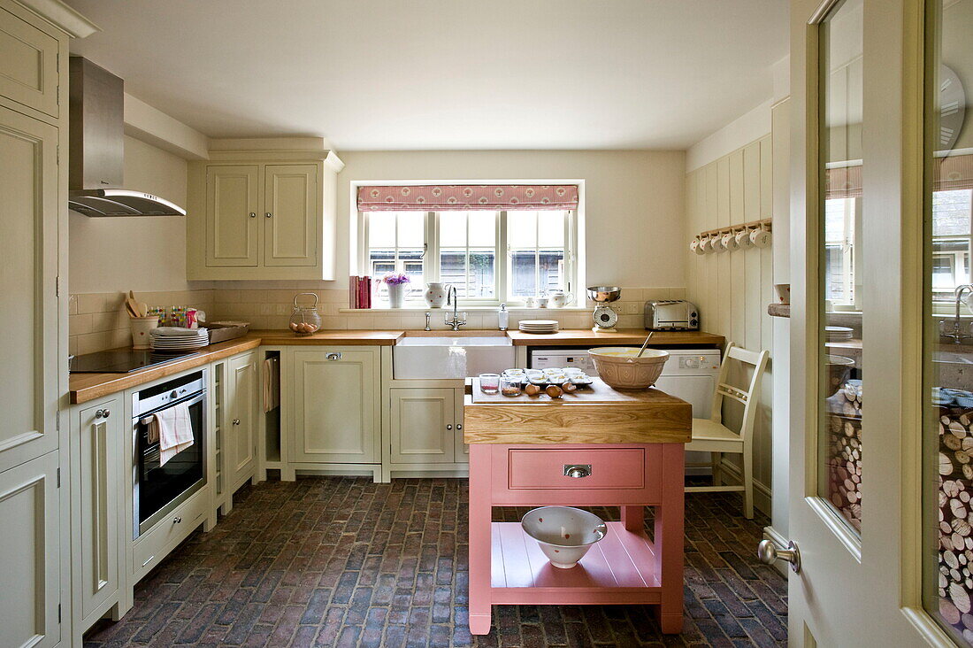 Fitted kitchen with original brick floor and pink butches block in Buckinghamshire home, England, UK