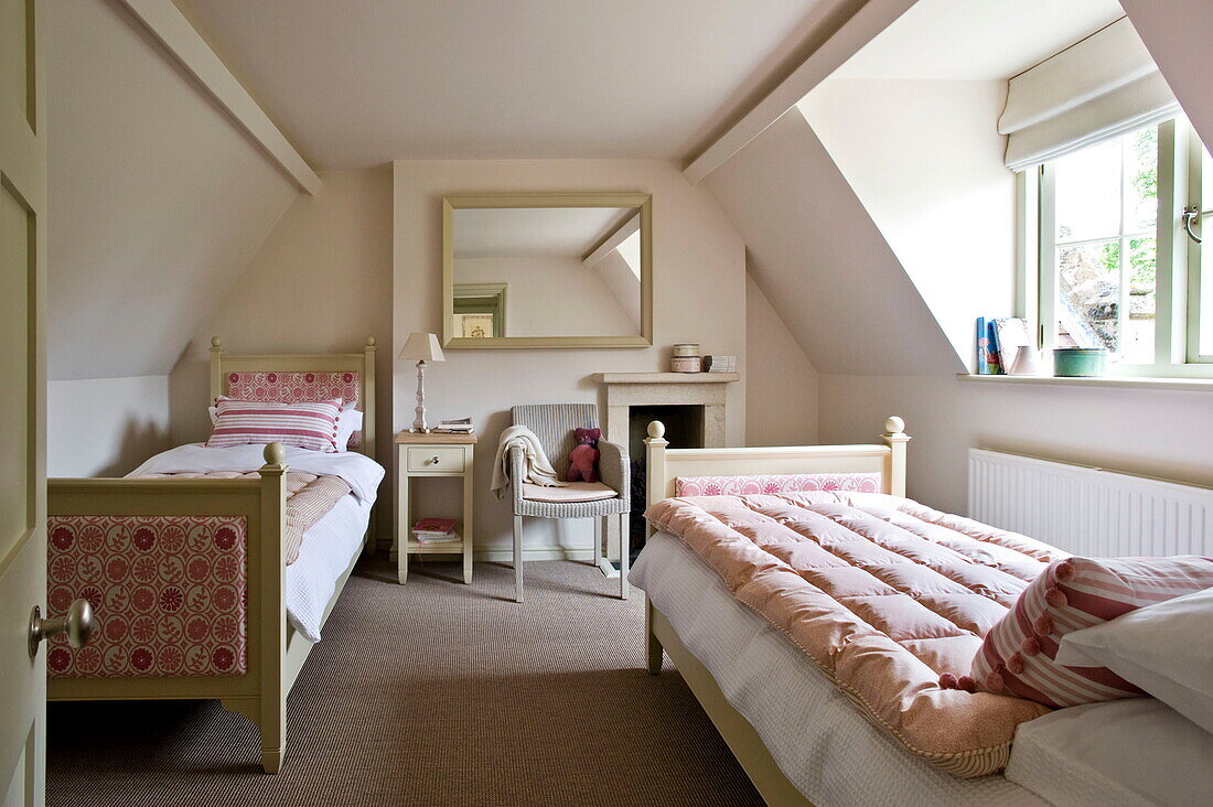 Zwillingsbetten mit gepolsterten Fuß- und Kopfteilen im Dachgeschoss eines Hauses in Buckinghamshire, England, UK