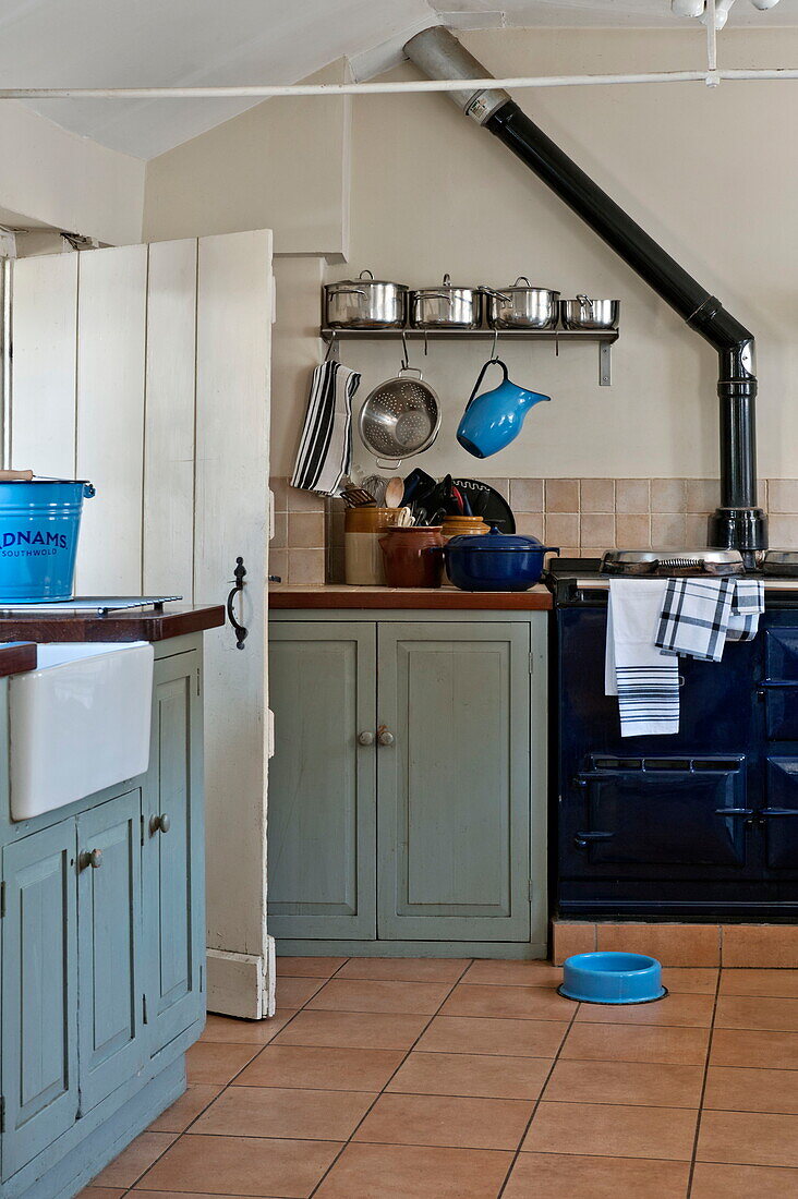 Hellblaues Küchengeschirr in einer gefliesten Küche mit lackierten Schränken in einem Bauernhaus in Suffolk, England, Vereinigtes Königreich