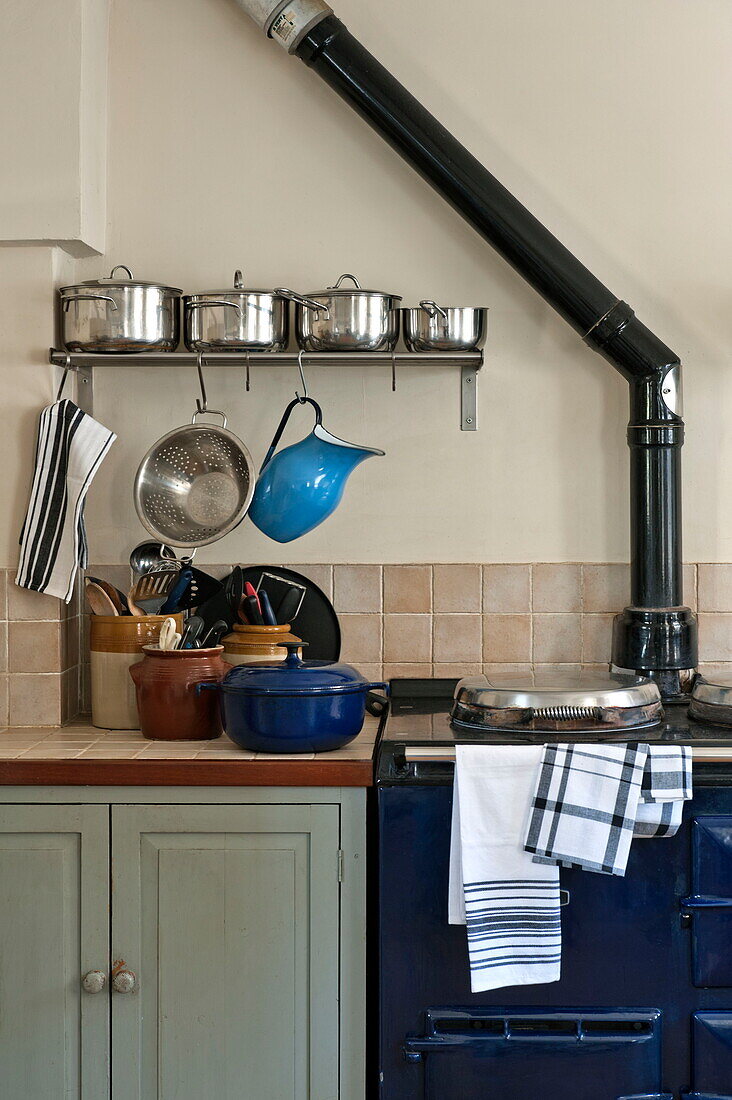 Saucepans and utensils on worktop next to oven in kitchen of Suffolk farmhouse, England, UK