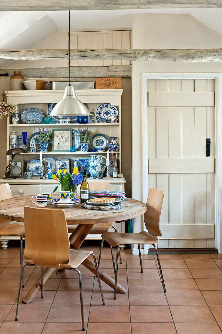 Runder Holztisch mit Kommode in gefliester Küche eines Bauernhauses in Suffolk, England, UK