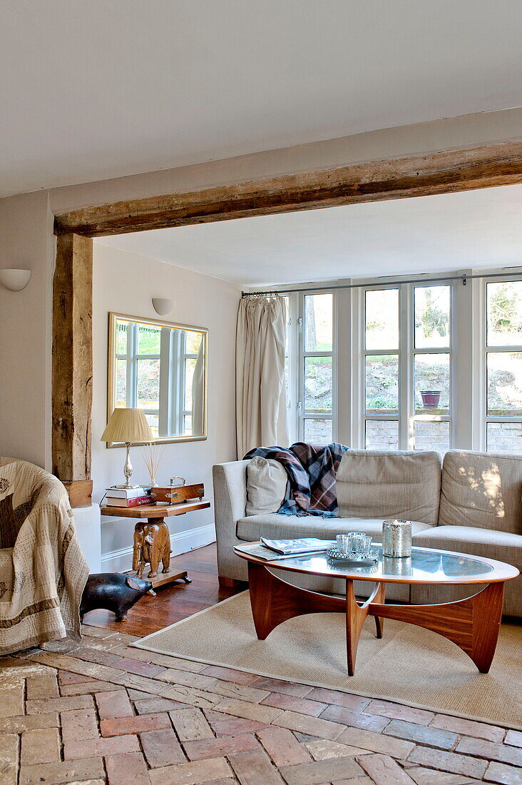 Fensternische in Holzrahmenbauweise mit Sofa und Tisch in einem Bauernhaus in Suffolk, England, Vereinigtes Königreich
