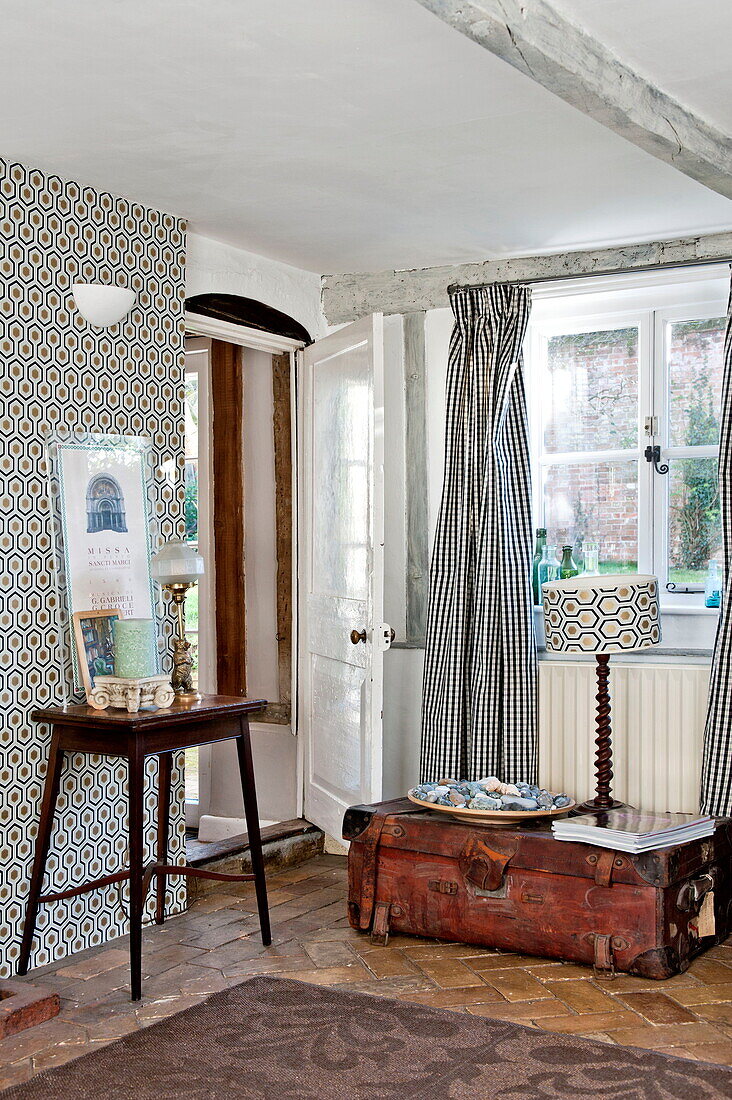Vintage suitcase and side table in room with retro style prints, Suffolk farmhouse, England, UK