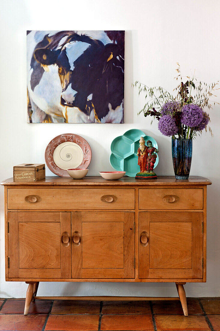 Kunstwerk auf Leinwand über hölzernem Sideboard in einem Haus in Hertfordshire, England, UK