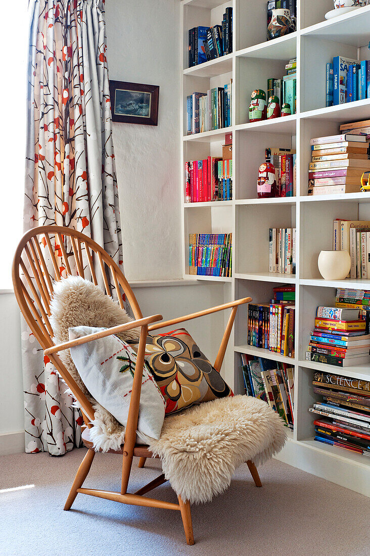 Pelzteppich auf einem Holzstuhl mit Bücherregal in einem Familienhaus in Hertfordshire, England, UK