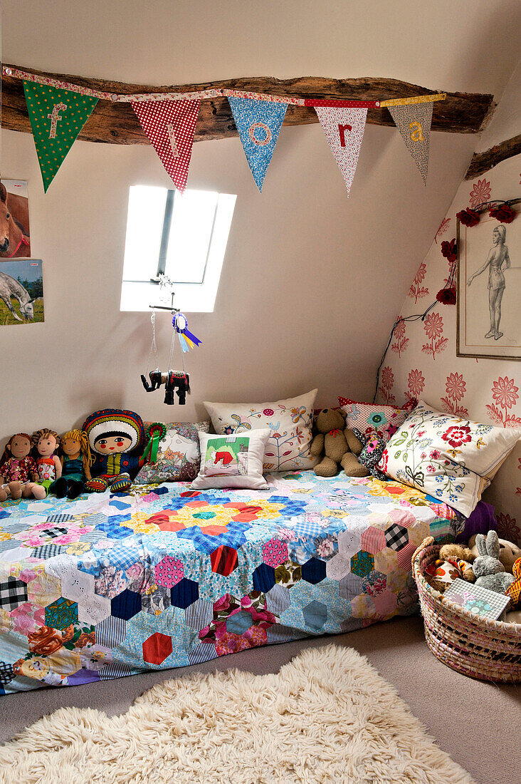 Soft toys on patchwork quilt on single bed of girl's attic room in Hertfordshire home, England, UK