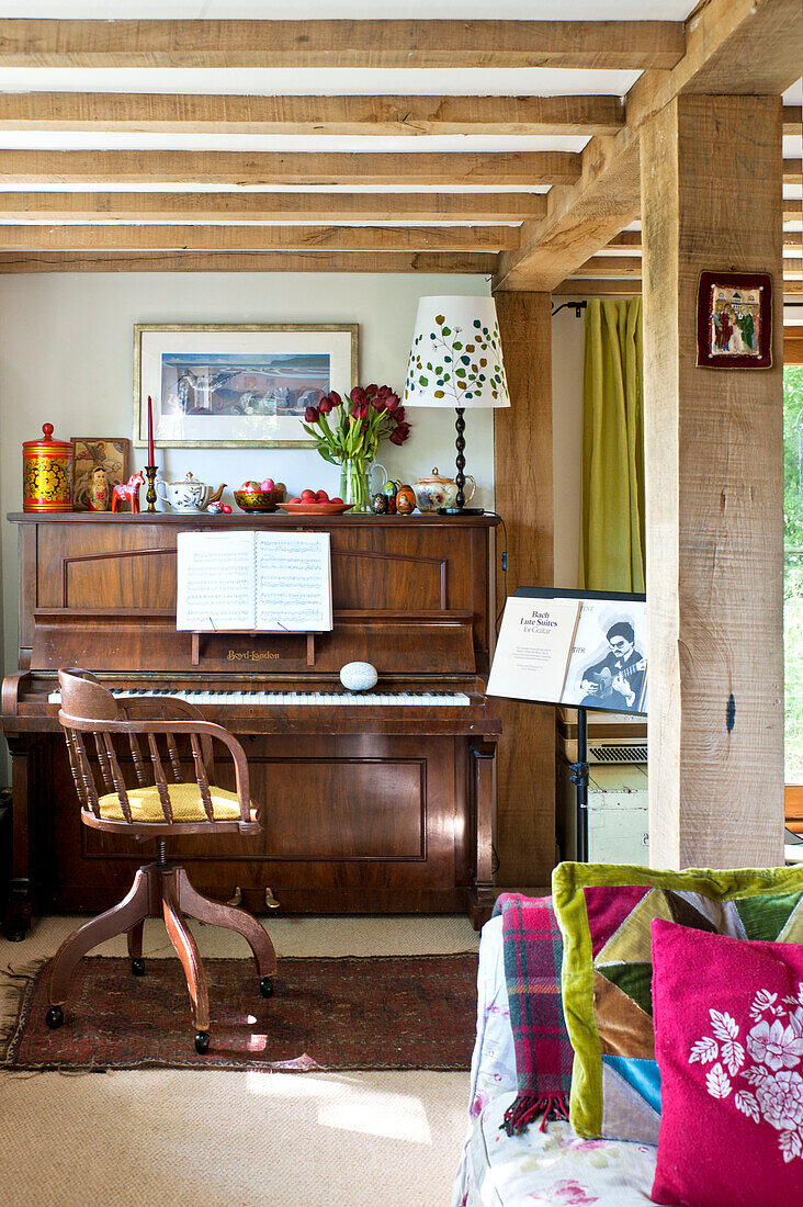 Klavier und Stuhl in einem Wohnzimmer mit Balken in einem Haus in Essex, England, UK