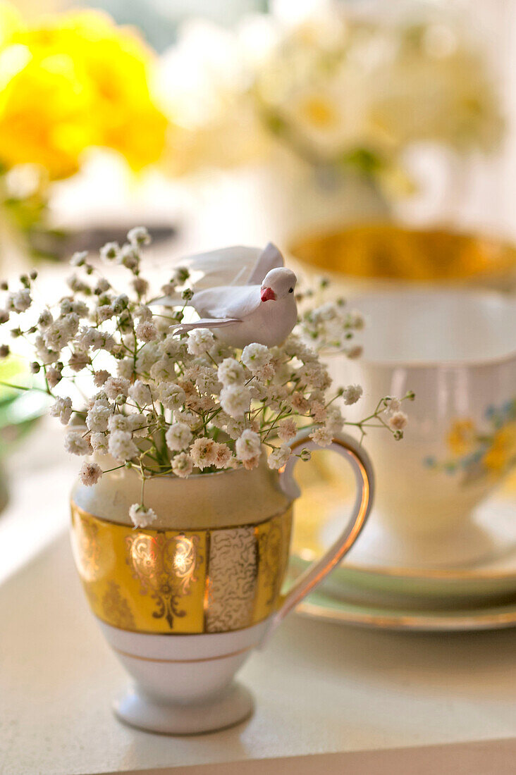 Künstlicher Vogel und geschnittene Frühlingsblüte im Milchkännchen, Haus in Essex, England, UK