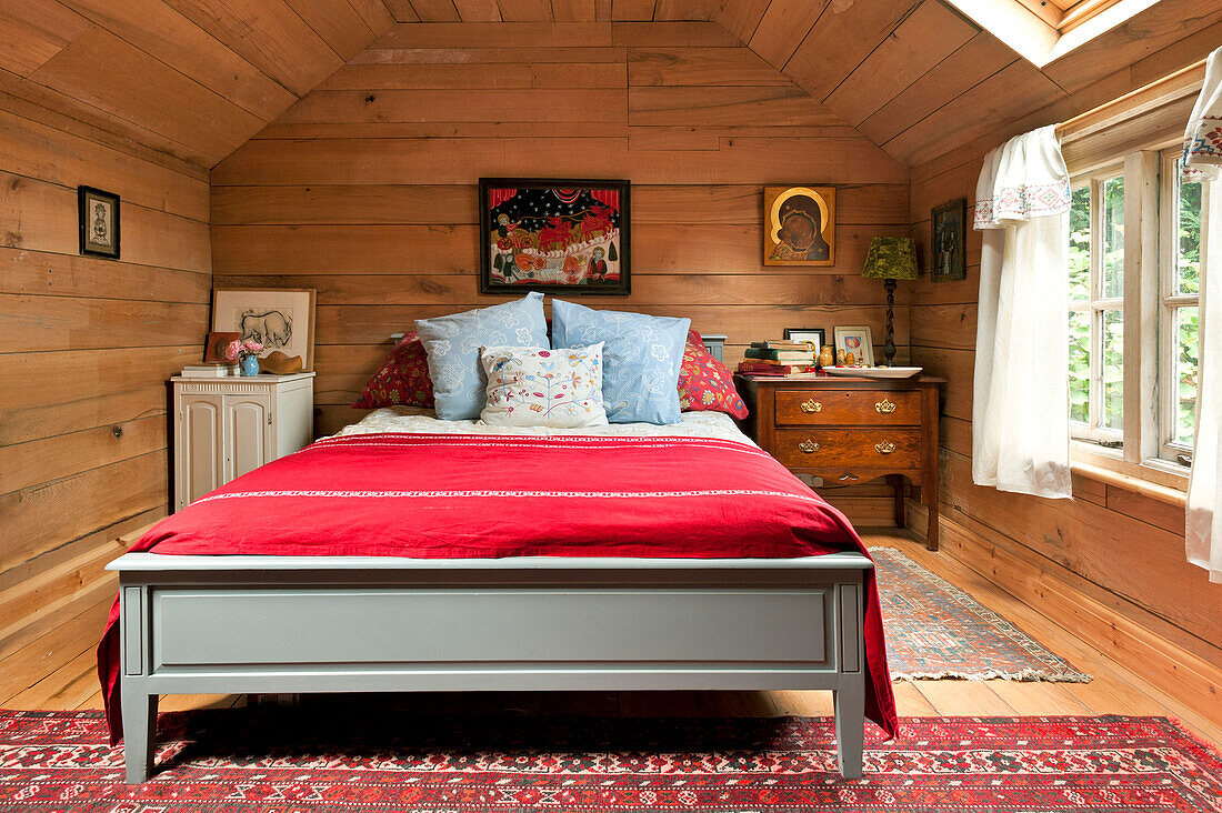 Red woollen blanket on double bed in wood clad bedroom of Essex home, England, UK