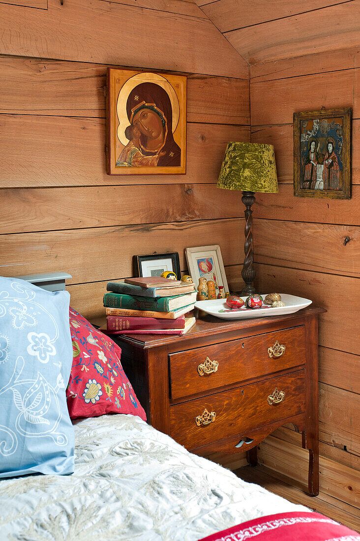 Bücher auf einer Holzkommode am Bett eines holzverkleideten Hauses in Essex, England, Vereinigtes Königreich