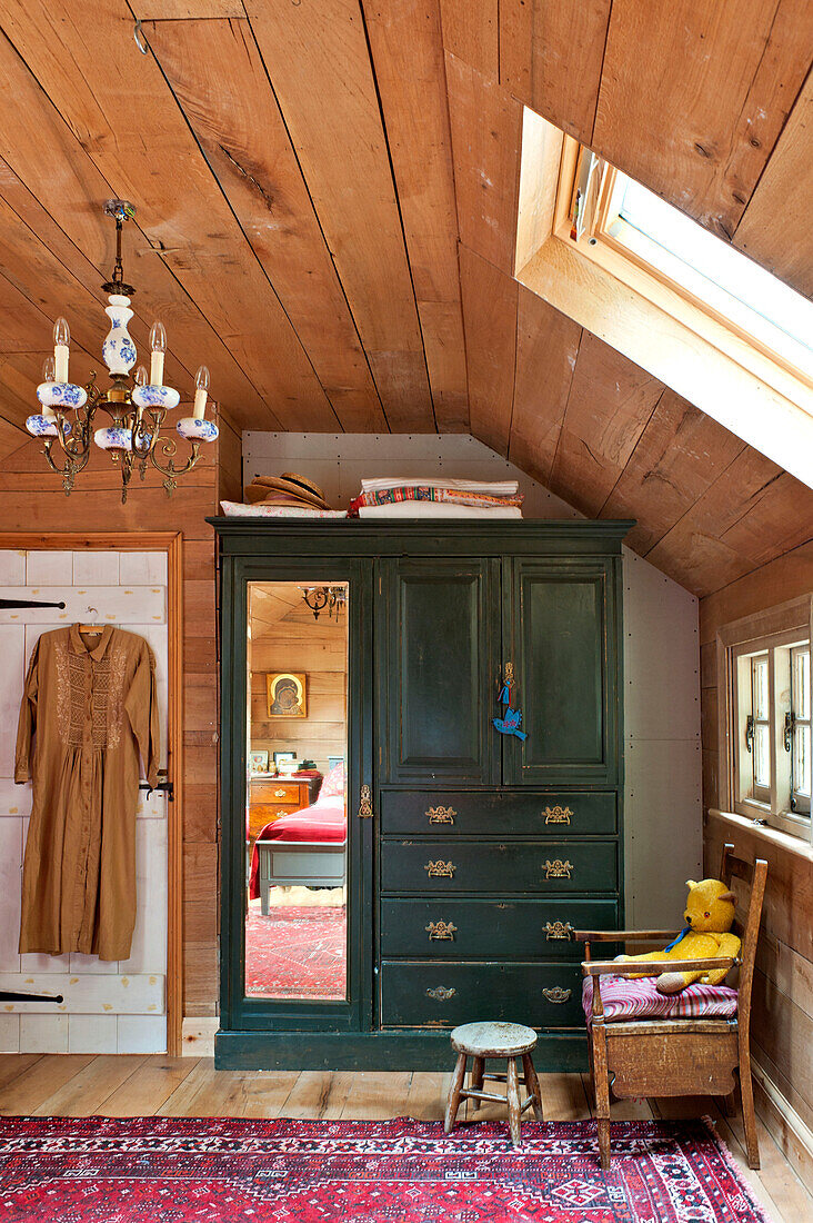 Green wardrobe with mirror and patterned rug in attic conversion of Essex home, England, UK