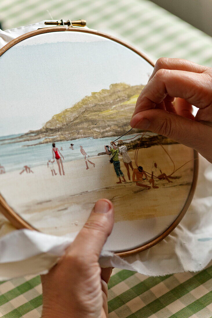 Woman working on tapestry of beach scene in Cornwall, England, UK