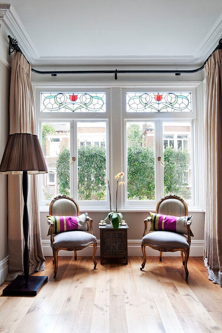 Antike Stühle im Fenster eines Familienhauses in Middlesex, London, England, UK