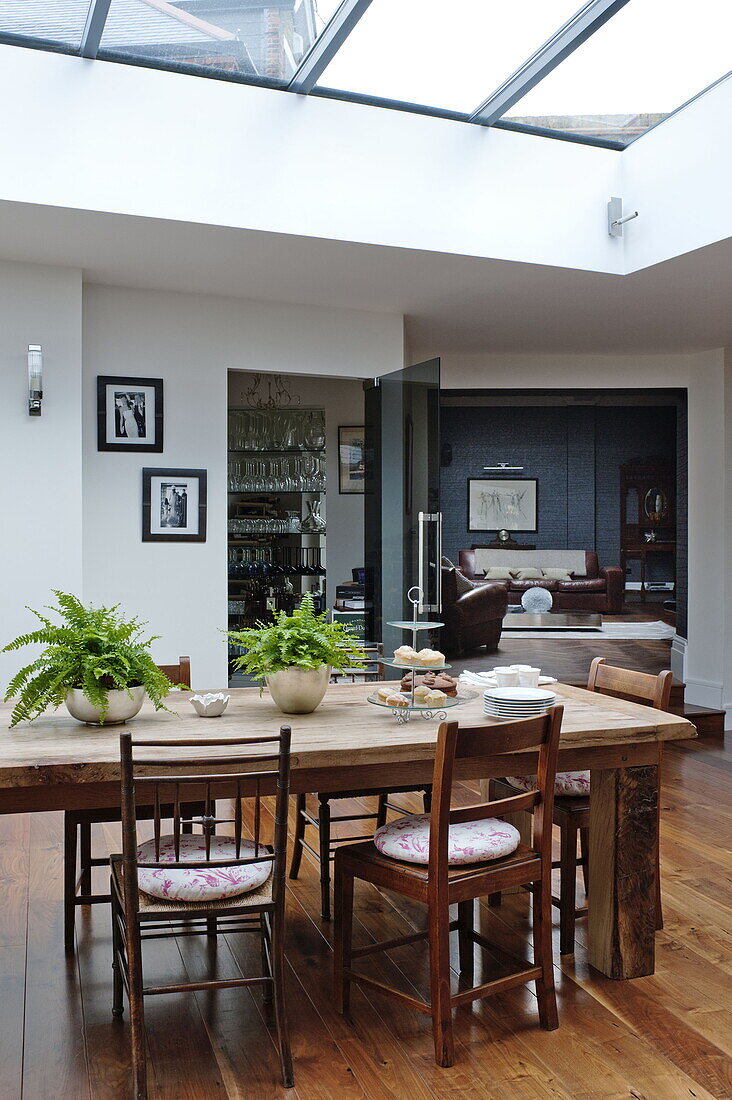 Wooden dining table and chairs with view to living room in London home, England, UK